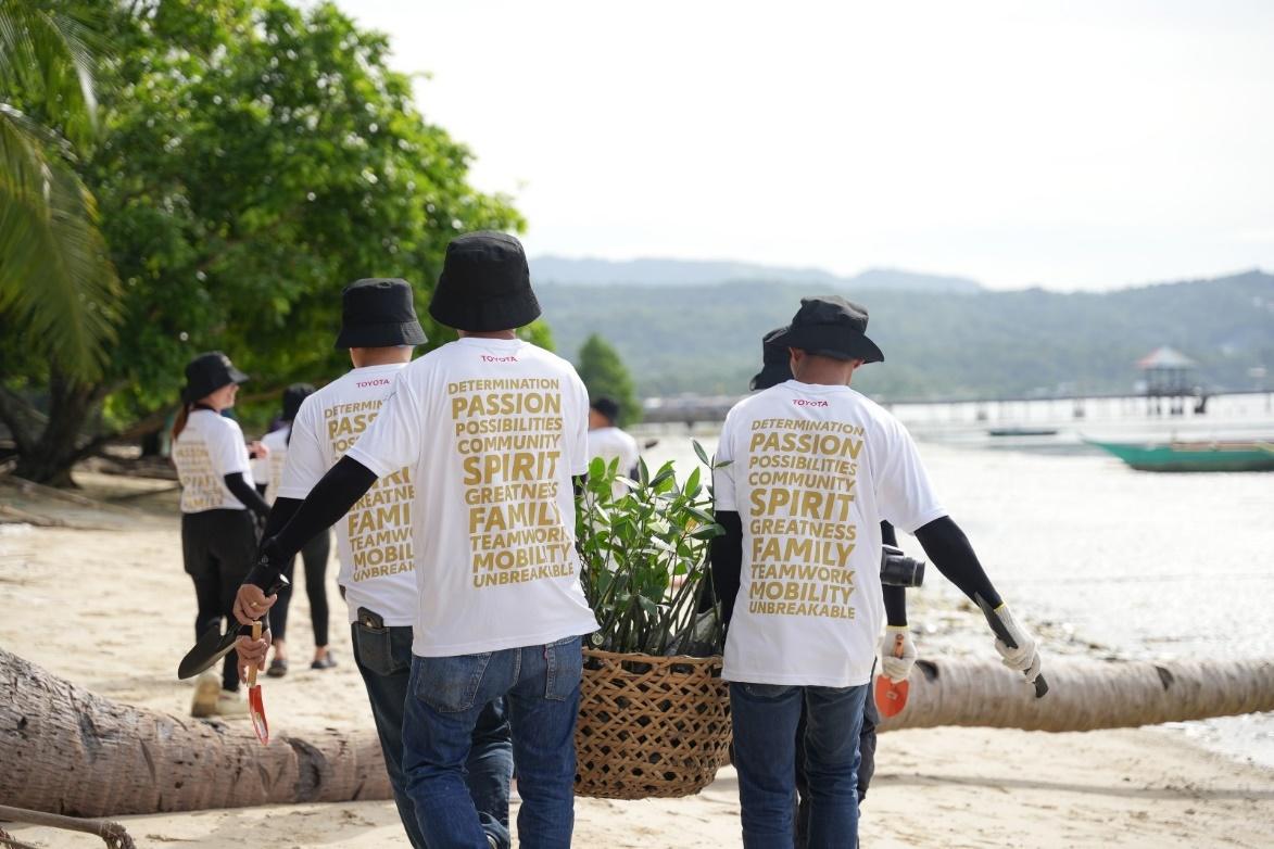 A group of people carrying a basket of plants

Description automatically generated