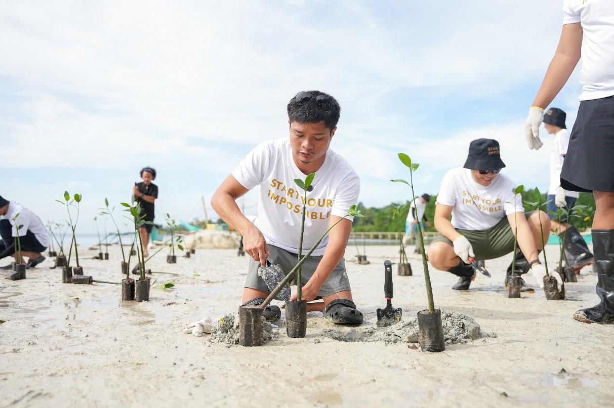 A group of people planting trees

Description automatically generated